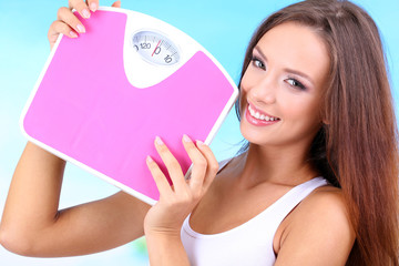 Wall Mural - Beautiful young woman with scales on blue background