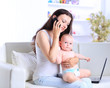 © yurolaitsalbert - Mother and baby in home office with laptop and telephone