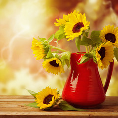 Wall Mural - Sunflower bouquet in jug on wooden table over autumn bokeh