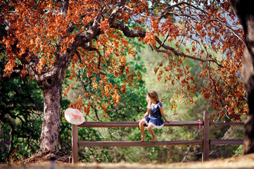 Pretty little girl relax on beauty autumn landscape background