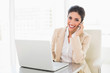 © lightwavemedia - Happy businesswoman working with a laptop on the phone
