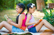 © spass - Sisters reading book in summer park
