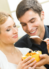 Wall Mural - Cheerful young couple with vegetarian salad at home