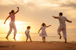 © altanaka - Happy family jumping on the beach on the dawn time