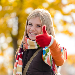 Wall Mural - Smiling autumn teenager girl thumbs up forest