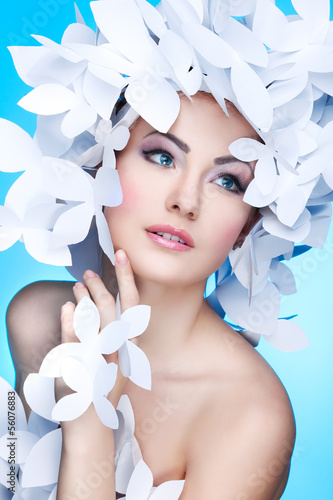 Fototapeta na wymiar Wonderful girl in a hat from paper white butterflies. On a blue 