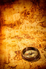 vintage compass lies on an ancient world map.