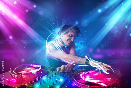 Plakat na papierze fotorealistycznym Energiczny dj miksujący muzykę z potężnymi efektami świetlnymi