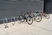 3 Bikes Are Locked To Modern Looking Sidewalk Racks In Toronto