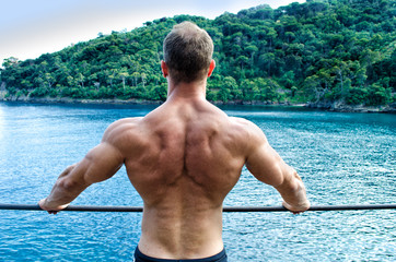 Muscular young man's back. Leaning on metal railing