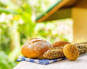 Fresh bread and checkered napkin on wooden table on rural backgr