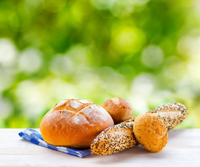 Fresh bread and checkered napkin on wooden table on rural backgr