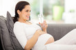 © michaeljung - pregnant woman drinking water while lying on a sofa