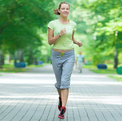 Wall Mural - Woman jogging in city street park.