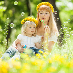 Happy mother and daughter blowing bubbles in the park