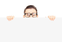 Scared Young Man With Glasses Hiding Behind A Blank Panel
