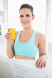 © lightwavemedia - Happy woman in sportswear holding orange juice