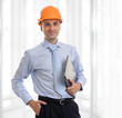 Young male architect wearing helmet and holding laptop
