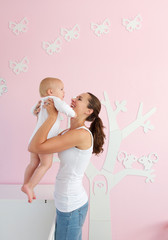 Happy young mother lifting baby from crib at home