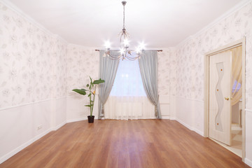 Spacious light room with chandelier and window with curtains