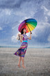 Barefooted woman with colorful umbrella under the rain