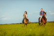© chesterF - couple riding on horses across the field