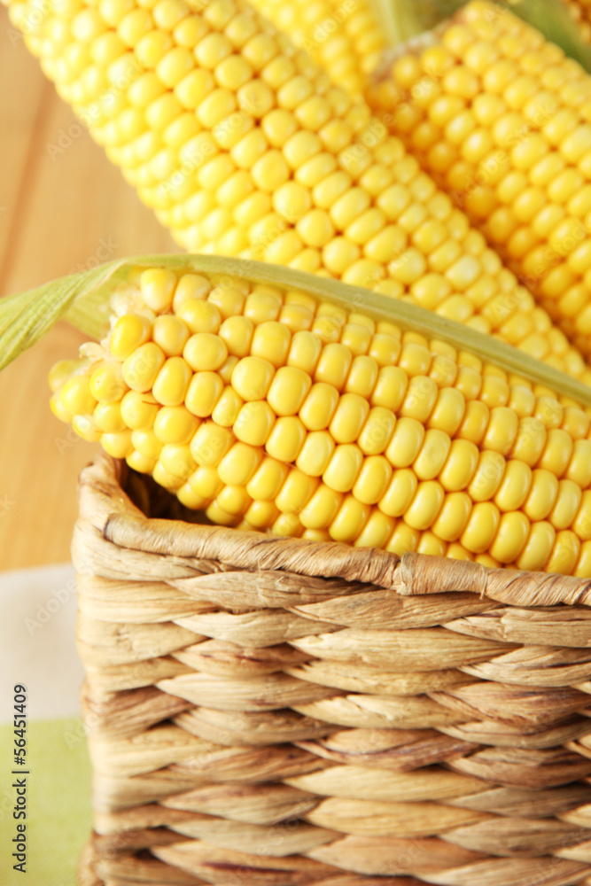 Crude corns in basket on napkin on wooden table
