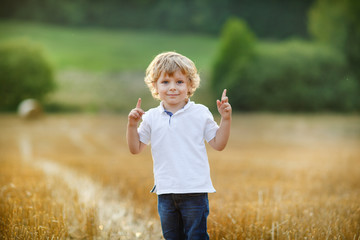 Wall Mural - Adorable blond little boy having fun on yellow hay field