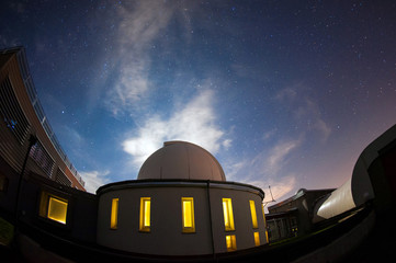 Astronomical observatory dome in the night with stars and glowin