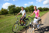 Fototapeta Przeznaczenie - Cheerful young couple riding bikes in countryside