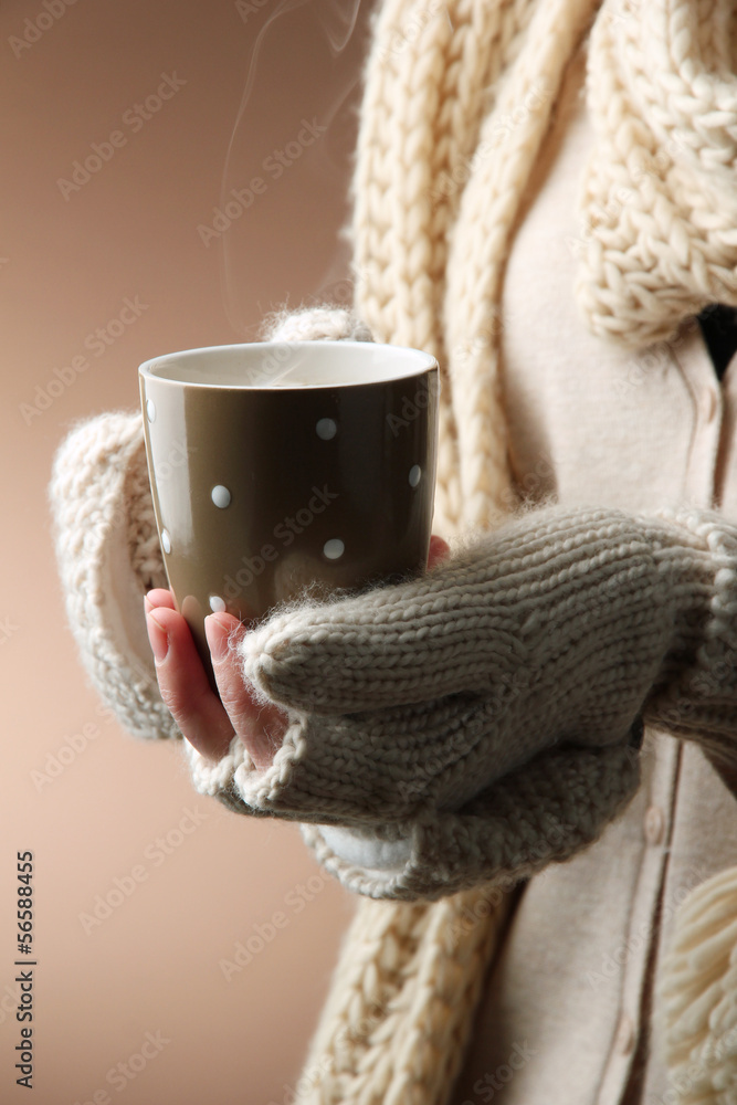 Female hands with hot drink, on color background