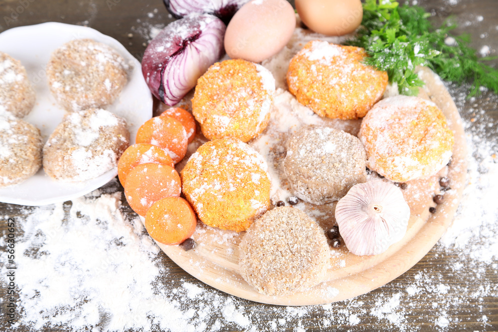 Meat patties on board on wooden table