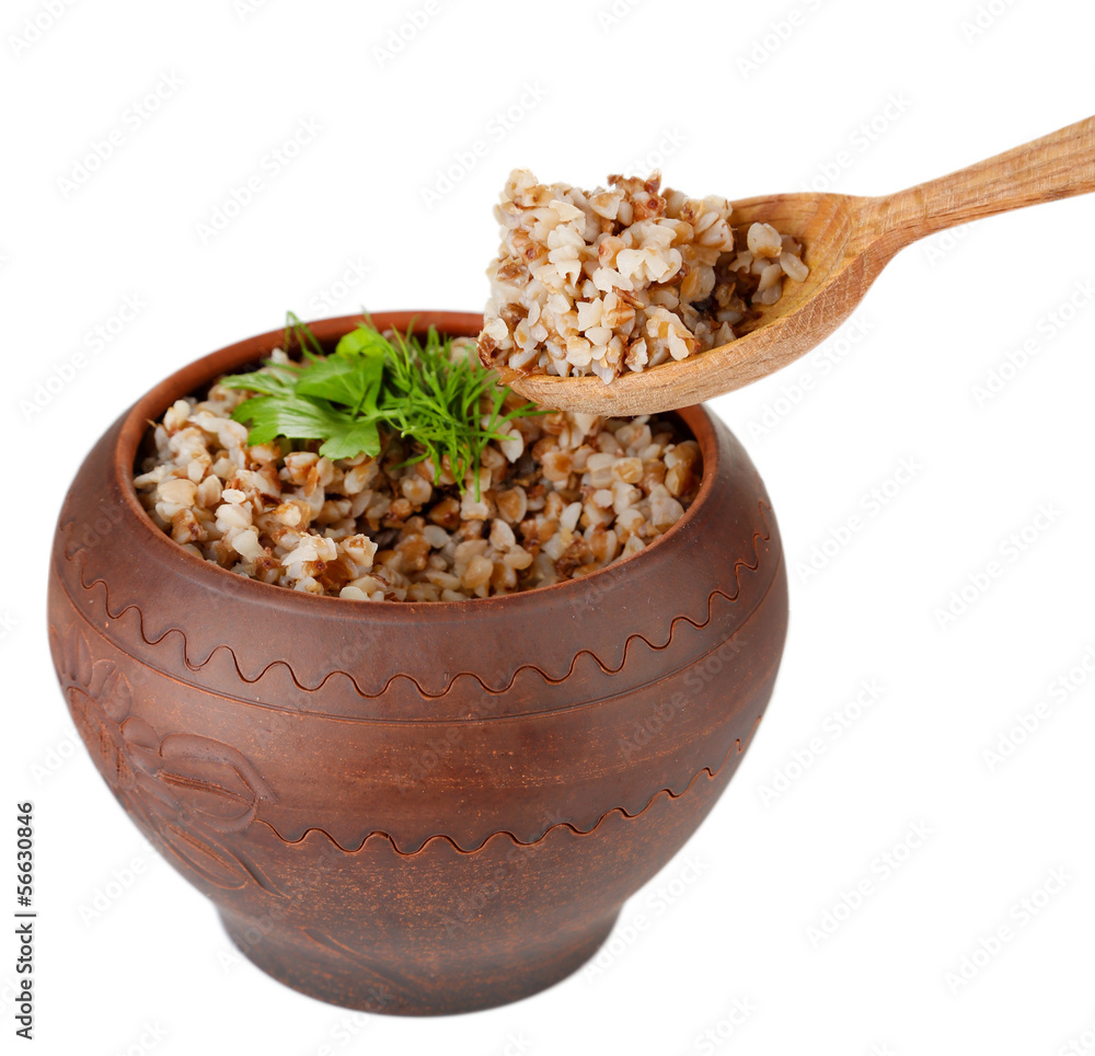 Buckwheat in pot and wooden spoon isolated on white