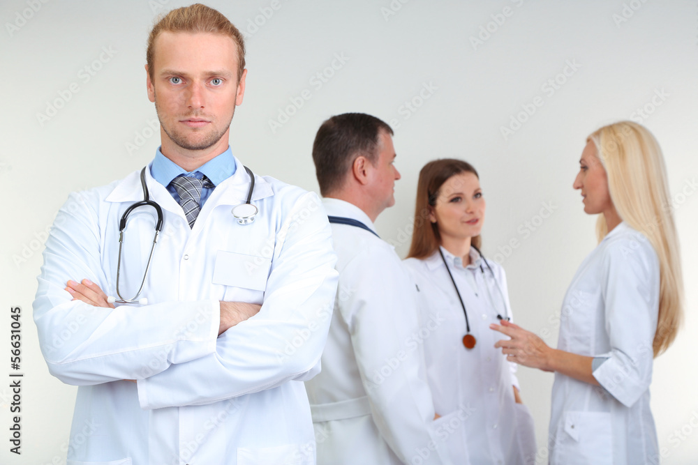 Doctor standing in front of coworkers on grey background