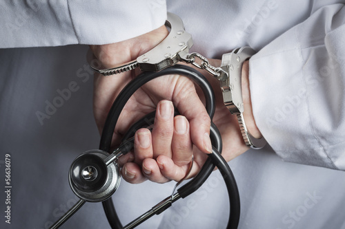 Fotografie, Obraz Female Doctor or Nurse In Handcuffs Holding Stethoscope