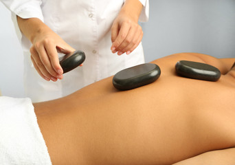 Young man having stone massage in spa salon