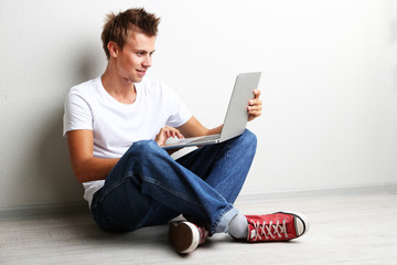 A handsome young man with laptop on grey background