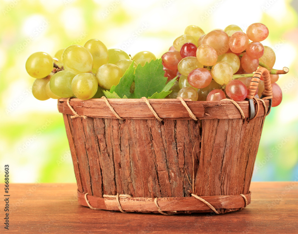 Ripe sweet grape in basket on wooden table, on nature