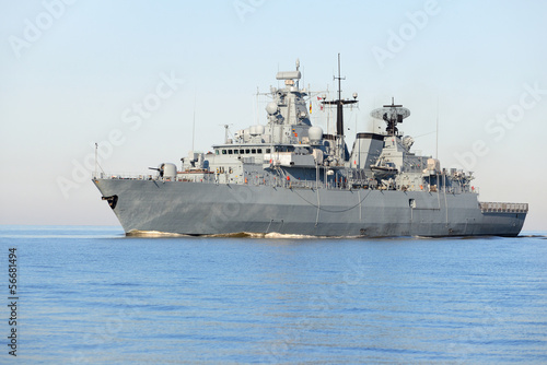 Fototapeta na wymiar Grey modern warship sailing in still water