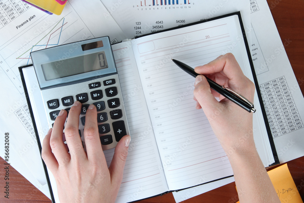Woman hands counting on calculator on worktable background