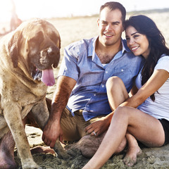 couple with pet dog on the beach