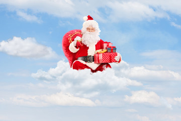 Poster - Santa Claus holding a bag full of presents on clouds