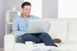 © WavebreakMediaMicro - Content casual man sitting on couch using laptop