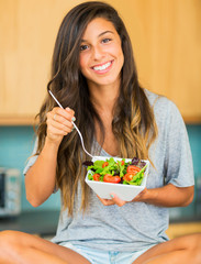 Beautiful young woman eating a bowl of healthy organic salad