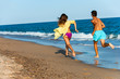 Teen couple chasing on beach.