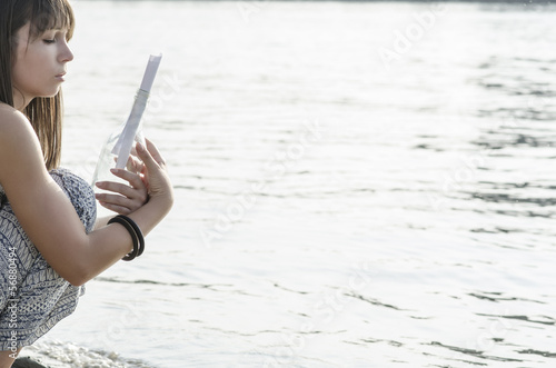 Sad young woman, holding message in the bottle. Poster