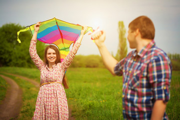 loving couple are fling a kite on a spring meadow