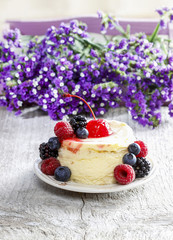 Wall Mural - Round cake with fresh fruits. Purple flowers in the background.