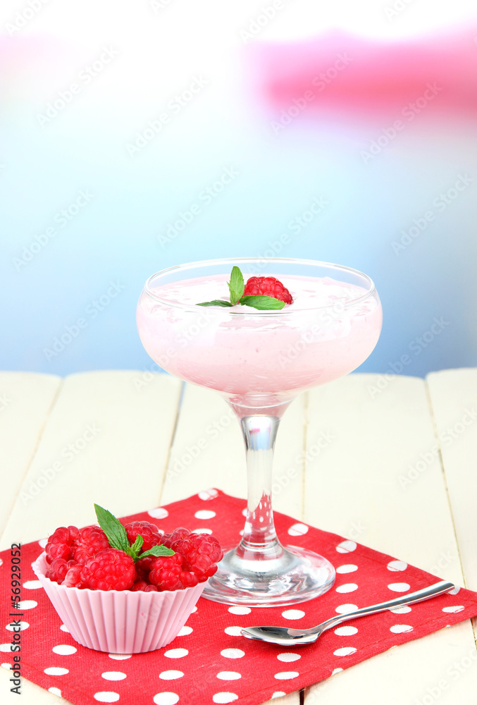 Raspberry milk dessert in cocktail glass, on light background