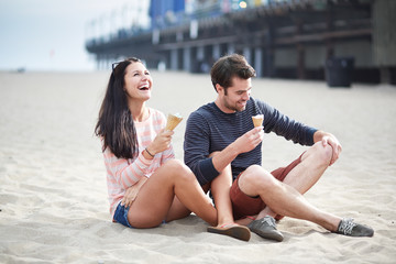 couple sitting in sand at sant monica pier.